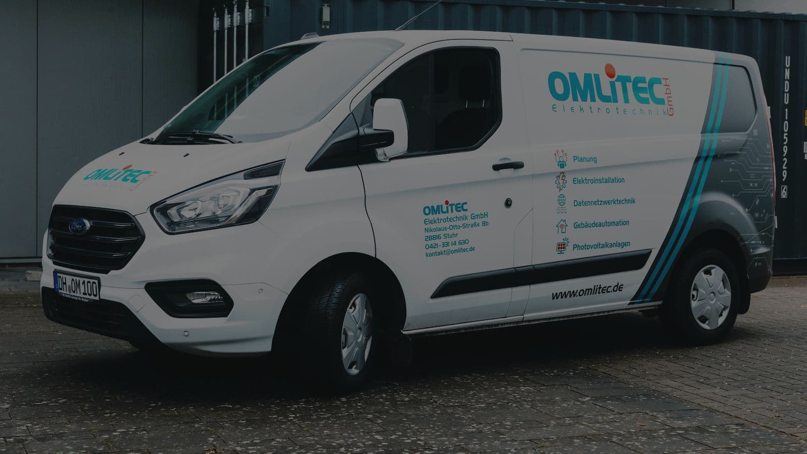 Firmenfahrzeug der OMLITEC Elektrotechnik GmbH mit Leistungsübersicht auf der Seitenwand